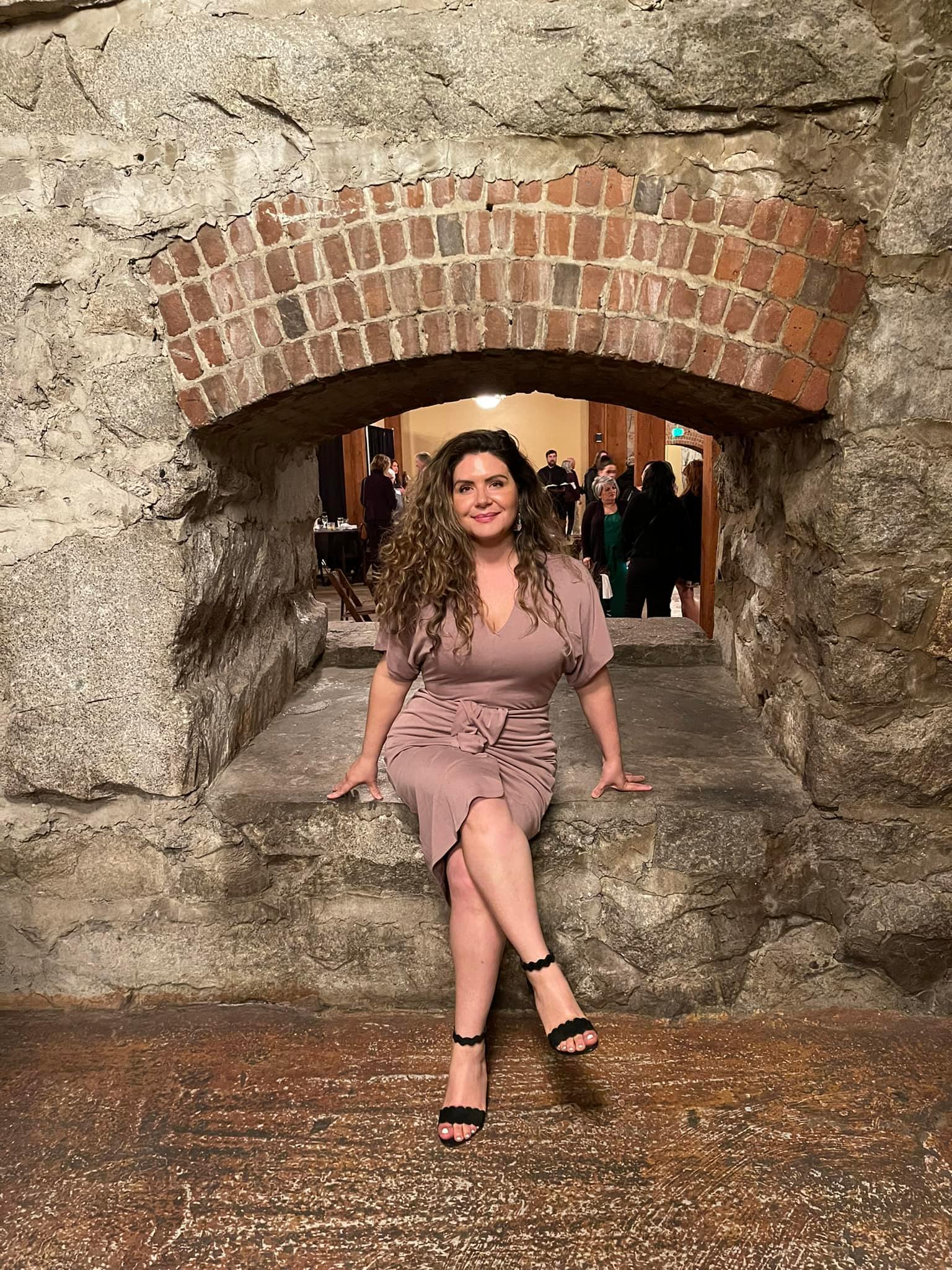 Photo of Jennyfer Mesa sitting on a stone fireplace at a professional event.