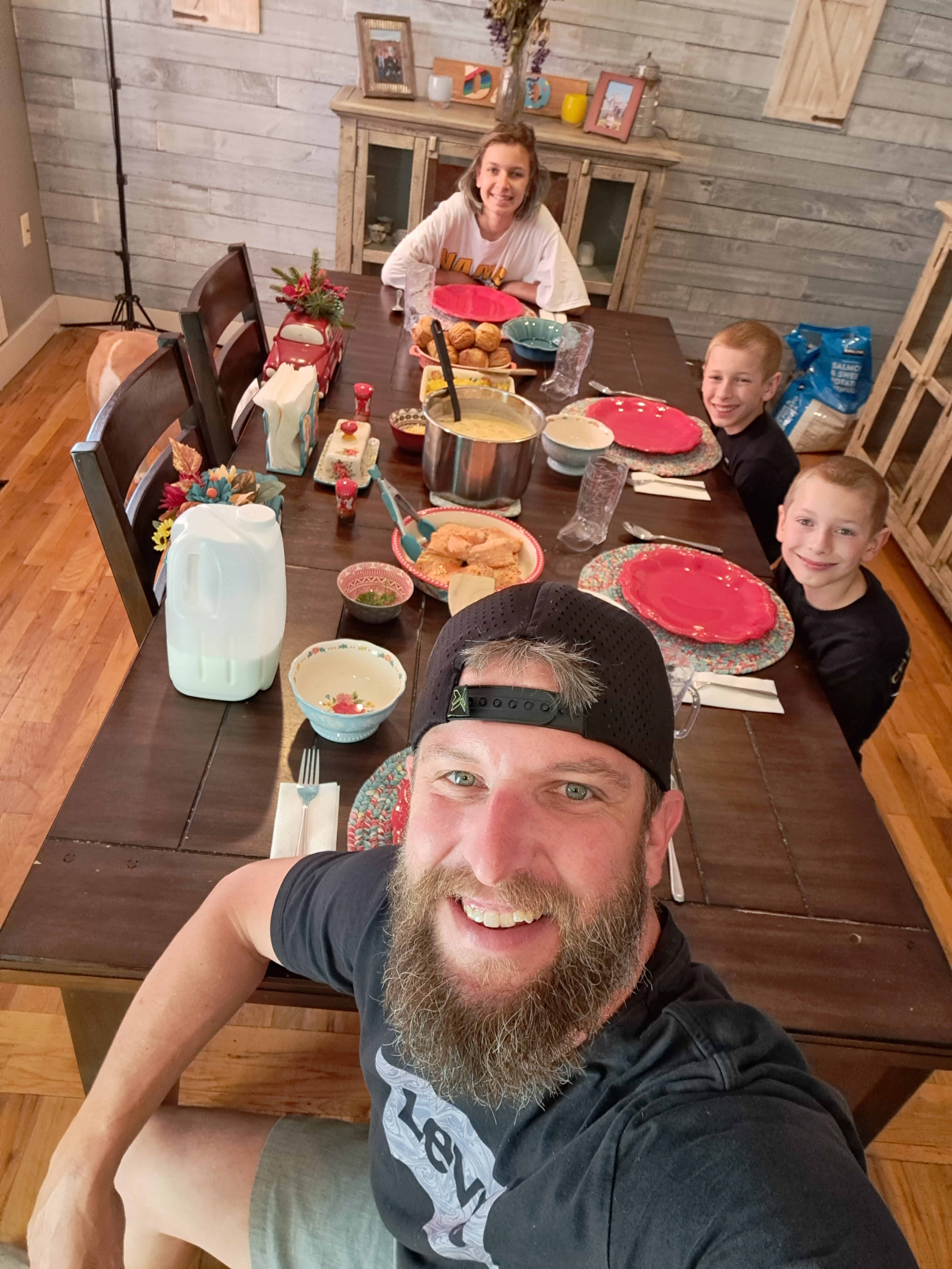 Tom of @DadsDinners sitting at a kitchen table with his family having dinner.