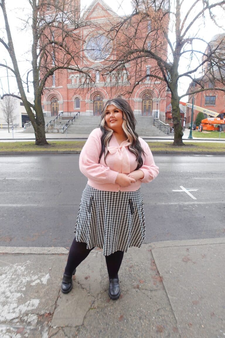 Author Shannon wearing a bright pink blouse with preppy skirt and black tights in downtown Spokane
