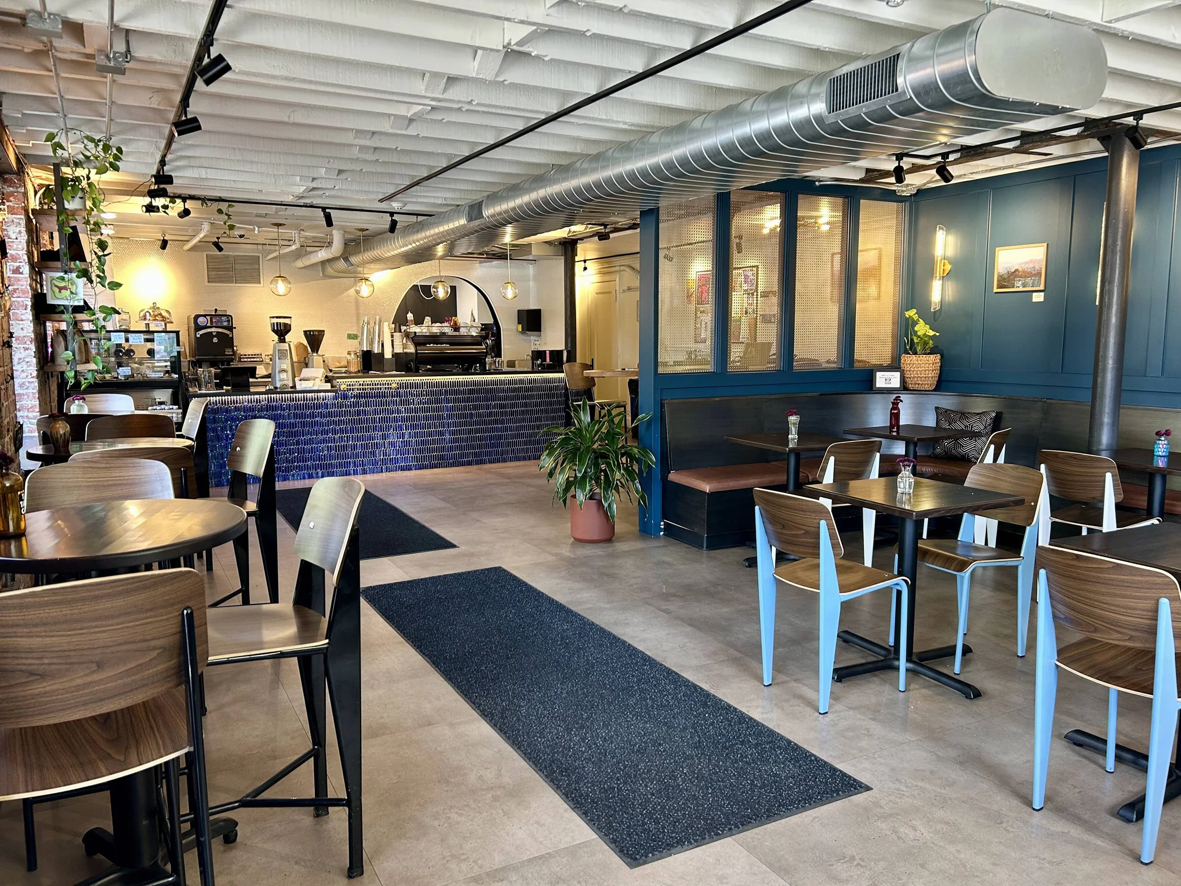 Inside Tay Tay’s Cafe, a royal blue tiled counter sits behind wooden tables and chairs under exposed ceiling beams.