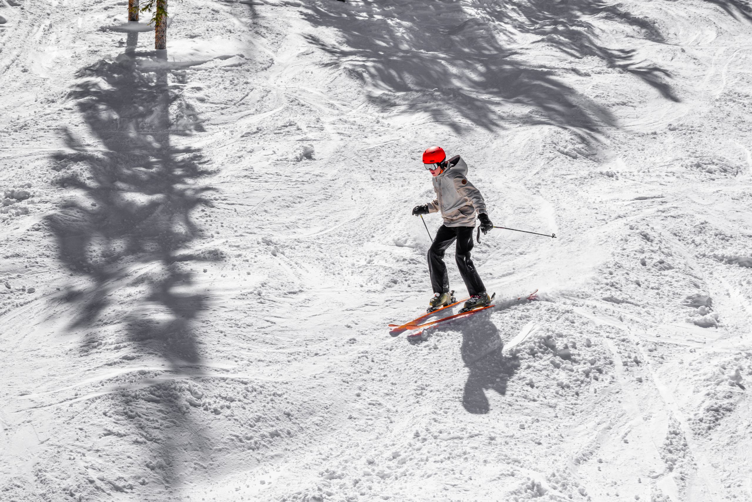 Skier with red helmet navigating a slope during winter in a scenic snowy landscape.